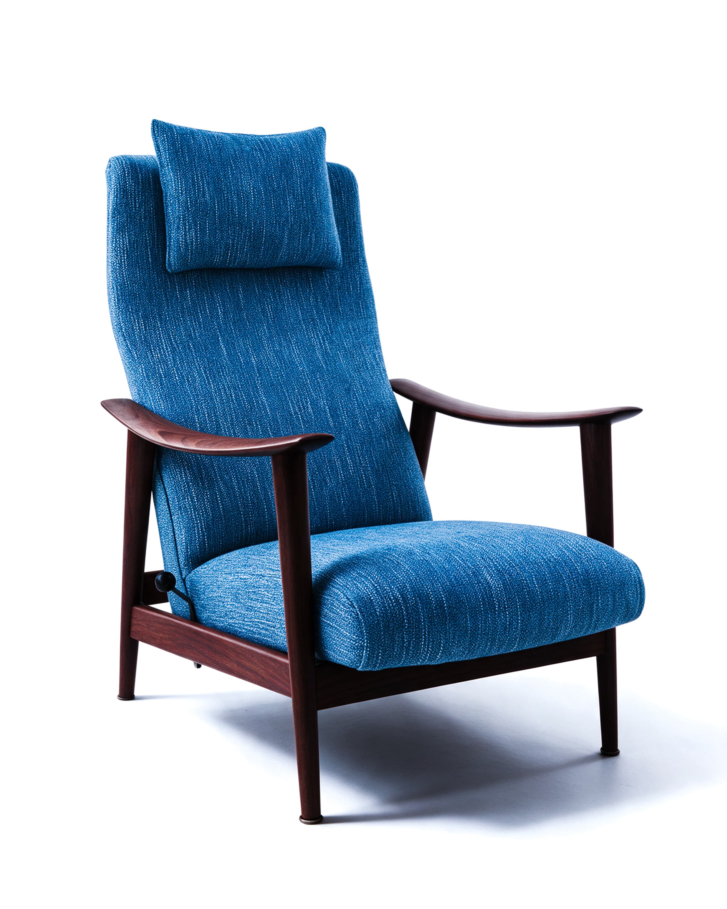 Fauteuil à haut dossier en bois sombre, garni d'un tissu bleu chiné, avec son coussin de tête, sur fond blanc.